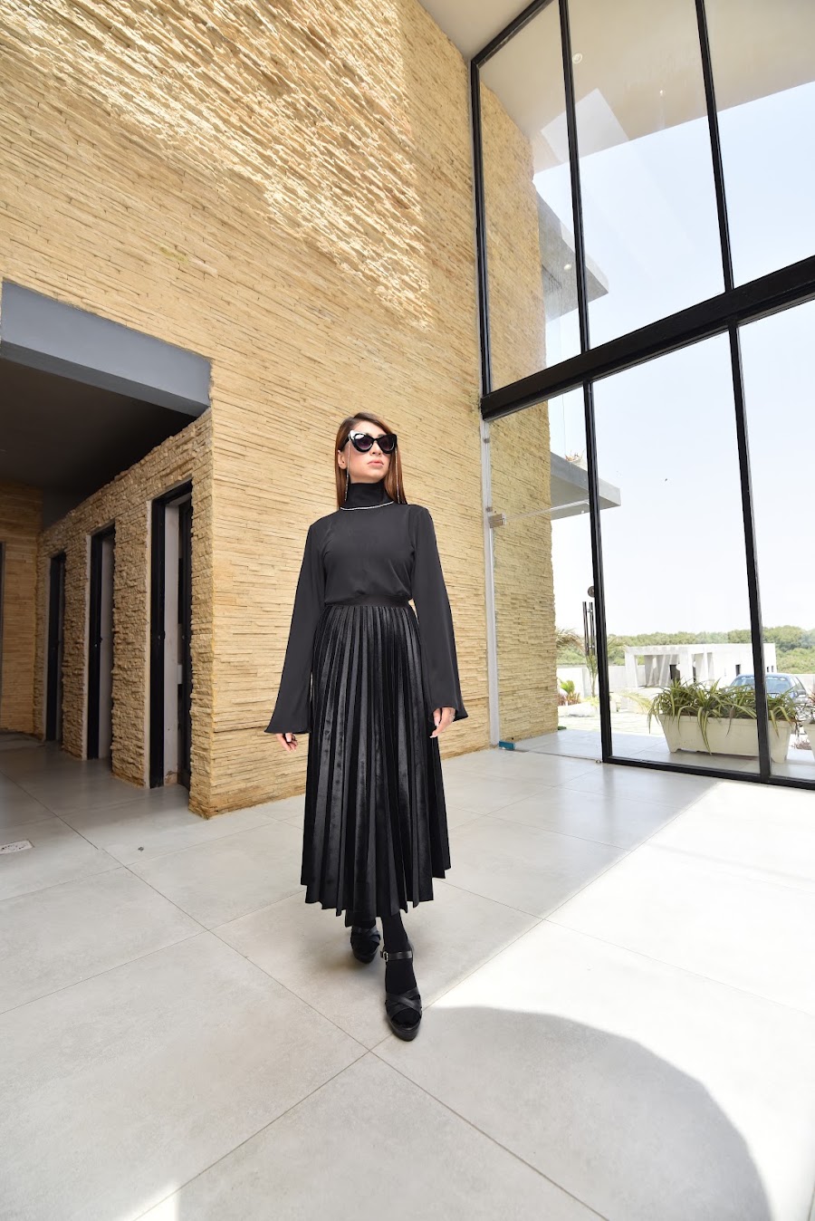 Nirvana campaign portrait of a model in a black dress beside architectural windows
